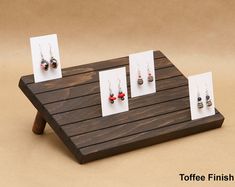 four pairs of earrings are placed on a wooden table with white cards attached to them