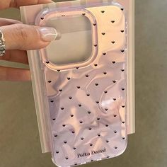 a hand holding a clear case with hearts on the front and sides, for an iphone