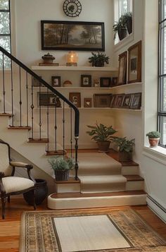 there is a stair case in the house with pictures on the wall and potted plants