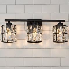 three lights that are on the side of a brick wall next to a white tiled wall