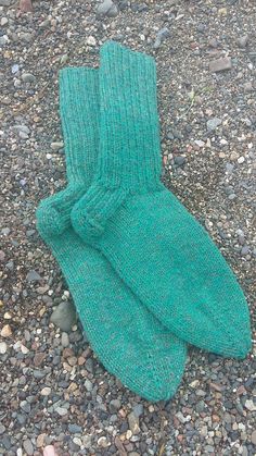 a pair of green socks laying on top of a gravel covered ground next to rocks