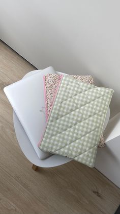 three pieces of cloth sitting on top of a white plate next to a wall and wooden floor