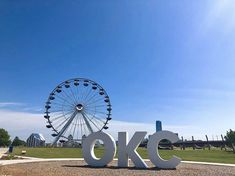 a large white sign that says ok with a ferris wheel in the back ground behind it