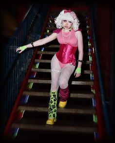 a woman dressed in pink and green is walking down some stairs