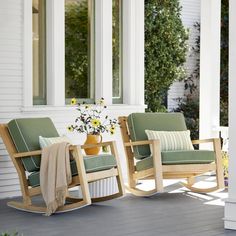 two rocking chairs on a porch with sunflowers in the vase next to them