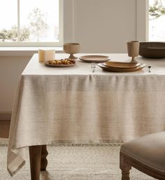 the table is set with plates and bowls on it, along with two candle holders