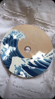 a cd that is sitting on top of a white cloth with blue and brown waves