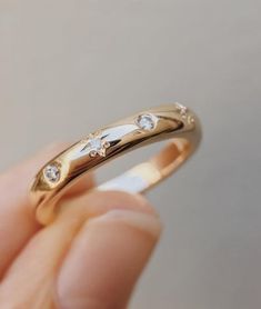 a person is holding a gold ring with three diamonds on the inside and outside of it