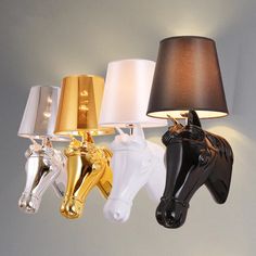 three horse head lamps are hanging on the wall next to a lamp that is turned on