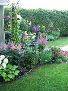 a garden filled with lots of different types of flowers and plants next to a house