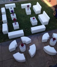 an outdoor seating area with flower arrangements and vases on the ground in front of it