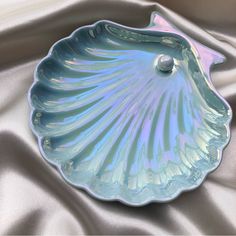 a blue shell shaped dish sitting on top of a silver cloth