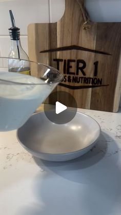 a glass filled with liquid sitting on top of a white plate next to a wooden cutting board