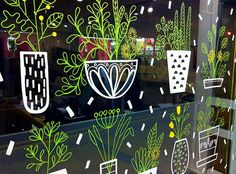 the window is decorated with plants and potted plants in black, green, and white colors