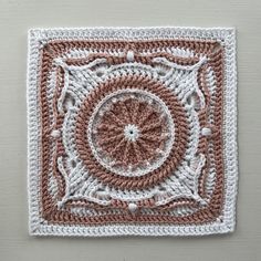 a crocheted square with a circular in the center on top of it, sitting on a wall