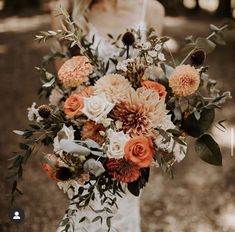 a woman holding a bouquet of flowers in her hands and wearing a white wedding dress