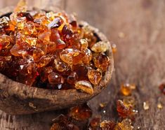 a wooden spoon filled with lots of brown and yellow sugar crystals on top of a table