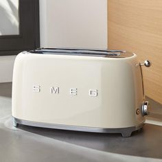 a toaster sitting on top of a counter next to a door way with the word smeg written on it