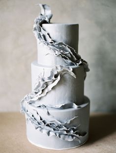 a three tiered white cake sitting on top of a table next to a wall