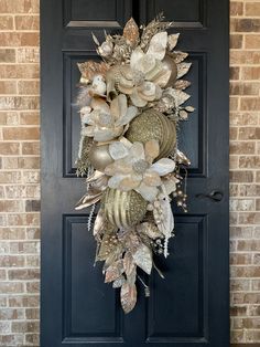 a wreath on the front door of a house that is decorated with gold and silver leaves