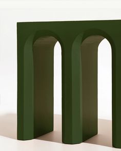 two green arches are standing next to each other in front of a white wall and floor