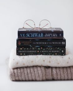 three books stacked on top of each other with glasses resting on the bookends