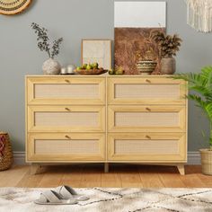 a wooden dresser sitting on top of a hard wood floor next to a potted plant