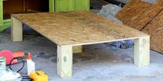 a wooden table sitting in the middle of a room next to some construction materials and tools