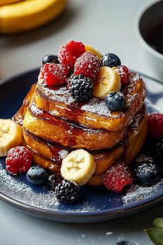 a stack of french toast topped with berries and banana slices on top of a blue plate