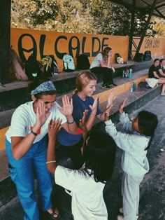 some people are standing and clapping in front of an orange wall with graffiti on it