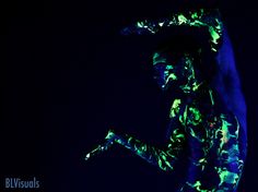 a man with his arms up in the air while wearing glow paint on his body