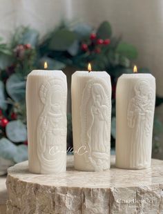 three white candles sitting on top of a stone slab