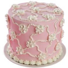 a pink cake with white flowers and pearls on the top is sitting on a plate