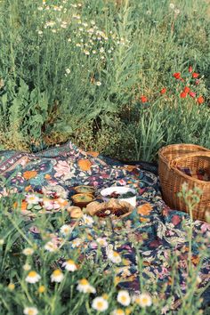 a basket sitting on top of a blanket in the middle of a flower filled field