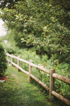 a wooden fence in the middle of a lush green field