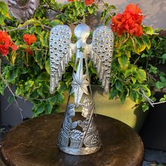 an angel figurine sitting on top of a wooden table next to potted plants