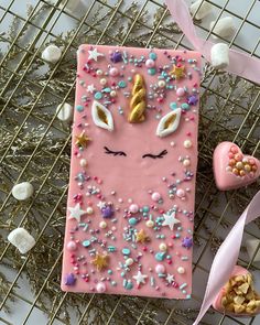 a pink phone case with unicorn face and stars on it next to other decorations, including marshmallows