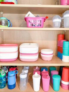 the shelves are filled with many different colored dishes and cups in plastic containers on them