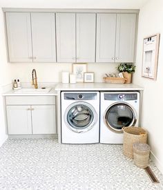 a washer and dryer in a white laundry room with gray cabinets on the wall