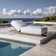 a white chaise lounge sitting on top of a swimming pool next to the ocean