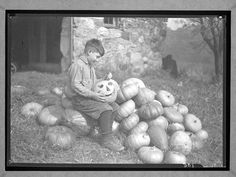 an old black and white photo of a boy with pumpkins