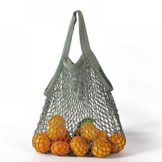 a mesh bag filled with oranges sitting on top of a white table