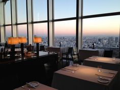 an empty restaurant with large windows overlooking the city