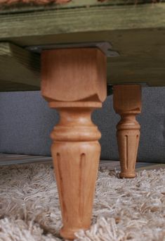 two wooden posts on the ground in front of a bed frame and carpeted floor