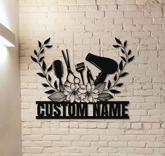 a sign that says custom name with flowers and hairdryers on it in front of a brick wall