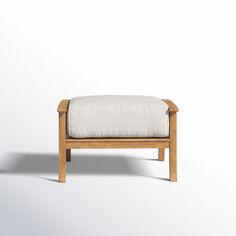 a small wooden bench with a white cushion on it's back and side, in front of a plain background