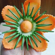 a hand holding an orange flower with green stems