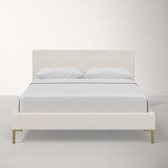 a bed with white sheets and pillows on top of it, in front of a wall