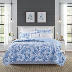 a blue and white bed in a bedroom next to two framed pictures on the wall