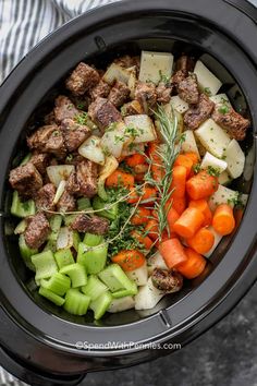 a slow cooker filled with meat, vegetables and carrots on a marble surface